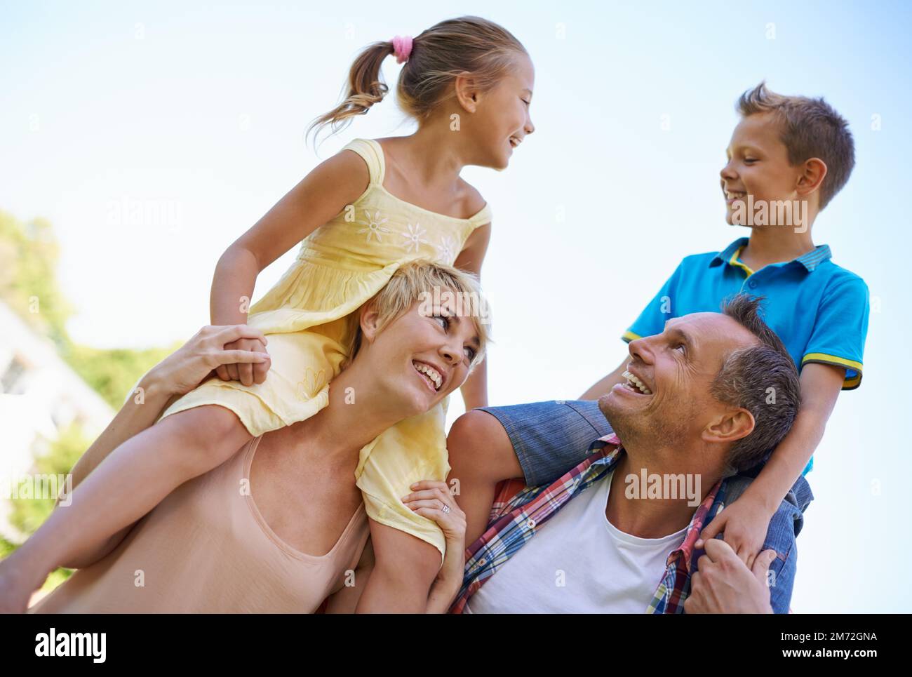 Due genitori orgogliosi. Un tiro corto di due genitori felici che trasportano i loro capretti giovani sulle loro spalle all'aperto. Foto Stock