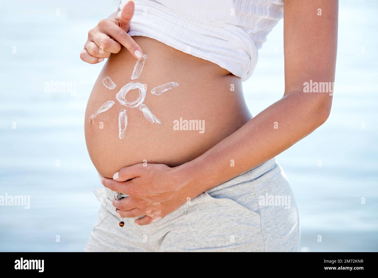 Incollaggio della ventre. una donna incinta con il sole attirato sul ventre sullo sfondo dell'oceano. Foto Stock