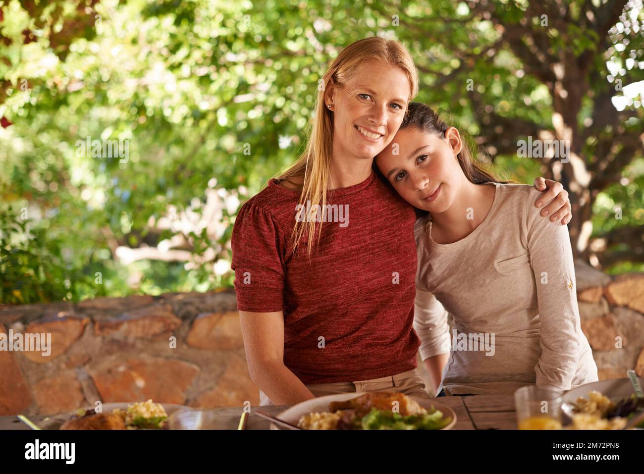 I pasti in famiglia sono pieni di ricordi speciali. Una donna e sua figlia che si godono un pasto in famiglia all'aperto. Foto Stock