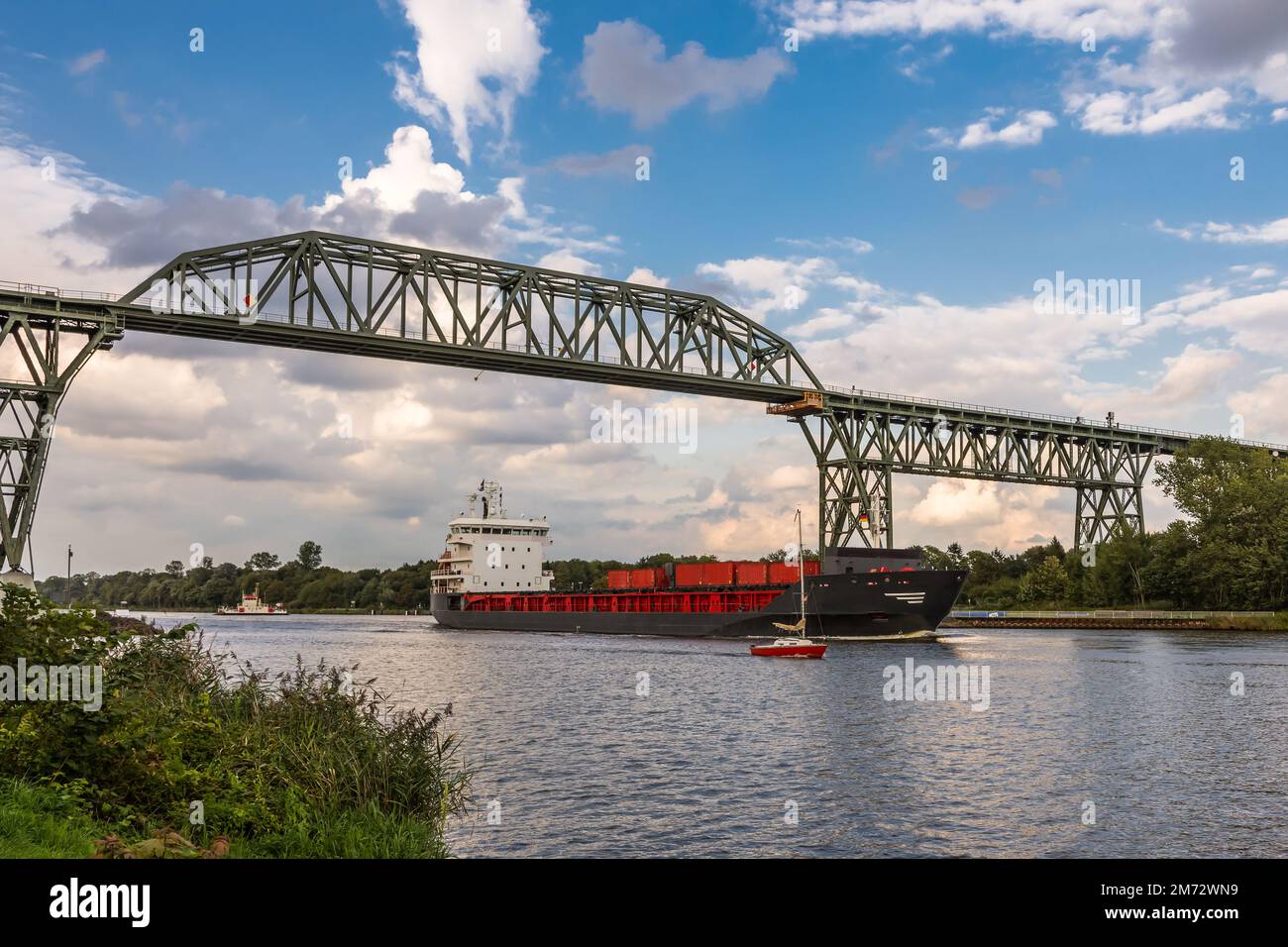 Nave da carico che passa sotto il ponte ferroviario Hochdonn sul canale Kiel, Schleswig-Holstein, Germania Foto Stock