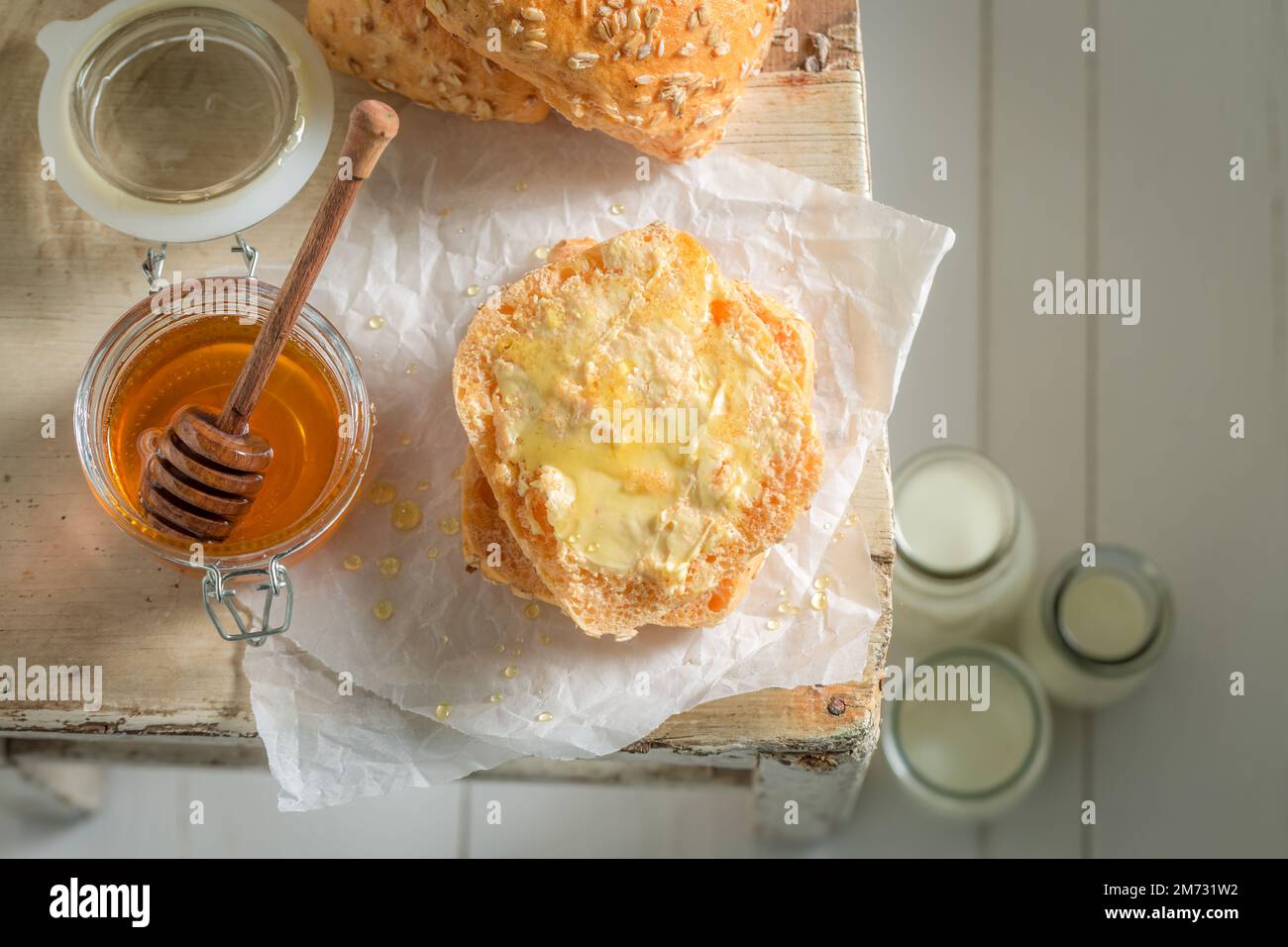 Panini integrali dolci e fatti in casa per colazione. Colazione con latte e miele. Foto Stock