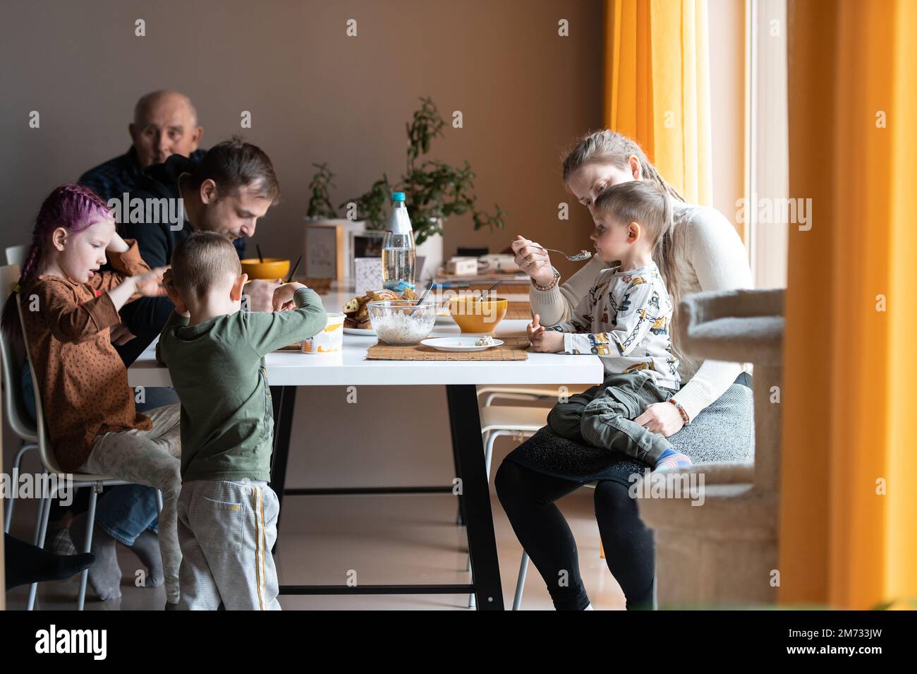 Famiglia multi generazione che mangia il pasto intorno al tavolo della cucina Foto Stock