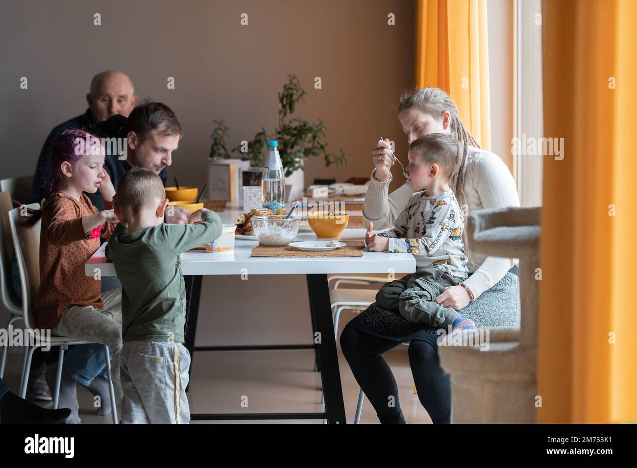 Famiglia multi generazione che mangia il pasto intorno al tavolo della cucina Foto Stock