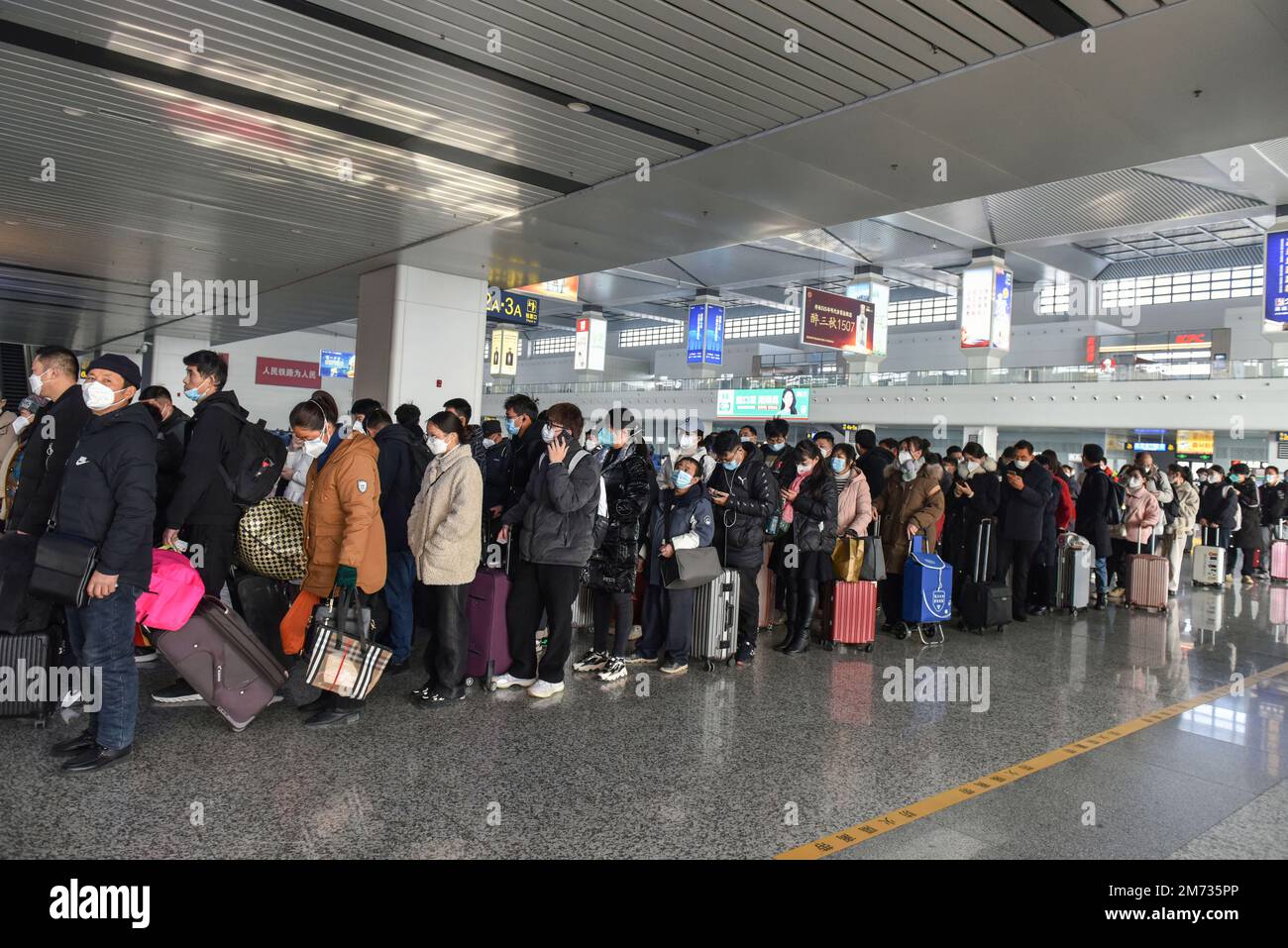 Passeggeri con maschere e valigie allineati nella sala d'attesa della stazione ferroviaria per ottenere il controllo dei biglietti. Circa 6,3 milioni di viaggi passeggeri sono previsti in tutta la Cina Sabato, il primo giorno di quest'anno di corsa al Festival di primavera, l'operatore ferroviario nazionale China state Railway Group ha detto. La Cina ha recentemente ottimizzato la sua gestione del controllo delle epidemie, e anche le misure epidemiche per i viaggi sono state ottimizzate il mese scorso. I viaggiatori non hanno più bisogno di risultati negativi dei test sugli acidi nucleici o di codici sanitari, non sono tenuti a sottoporsi a test sugli acidi nucleici o a controlli sanitari su AR Foto Stock