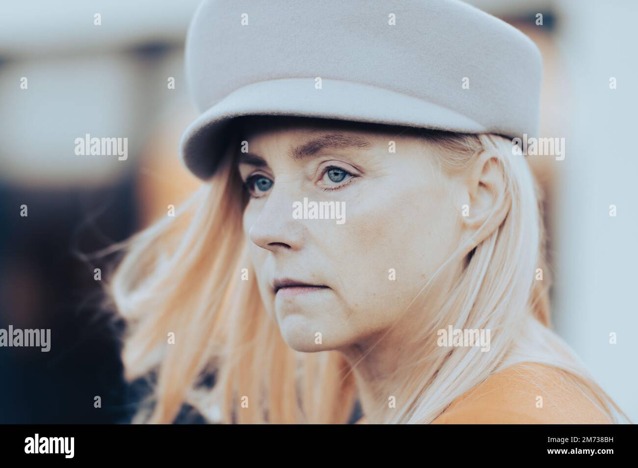 Primo piano volto ritratto europeo donna di mezza età con occhi verdi blu in cappello moda autunno Foto Stock