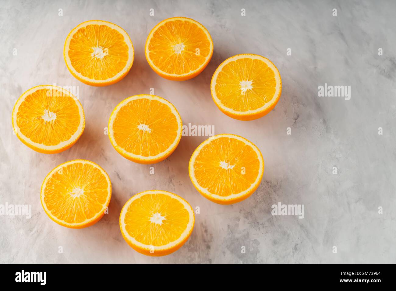 Metà di arance mature su fondo grigio. Arance a fette su cemento. Spazio di copia Foto Stock