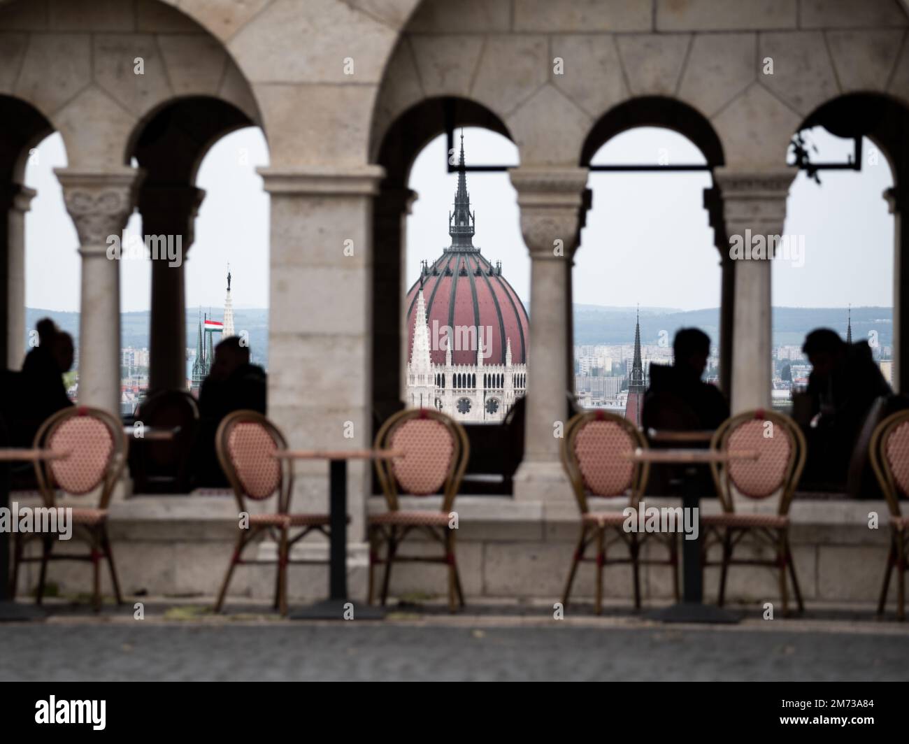 Le sagome delle persone sedute in un ristorante con lo sfondo del palazzo del parlamento di Budapest Foto Stock