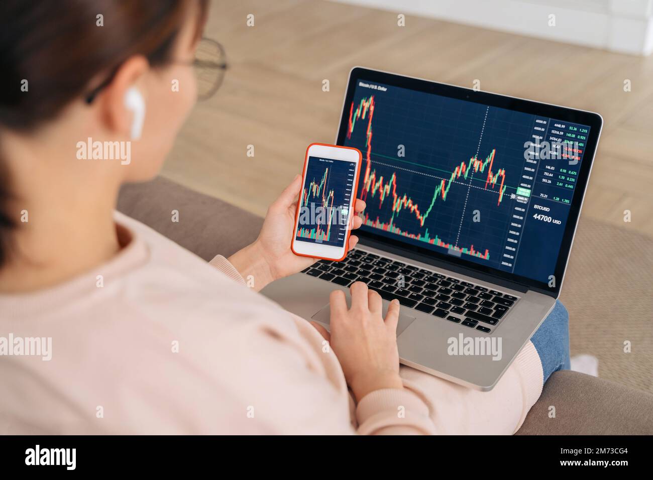 Primo piano dell'analista degli investitori di una donna commerciale che guarda alle classifiche del mercato azionario finanziario rate dinamico, utilizzando l'app per laptop e smartphone per l'analisi digitale della criptovaluta, acquistando criptovaluta Foto Stock