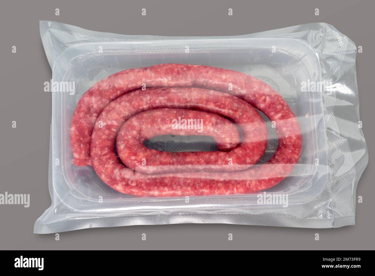 Salsiccia cruda confezionata sottovuoto sigillata per una cucina sous vide isolata su sfondo grigio in vista dall'alto Foto Stock
