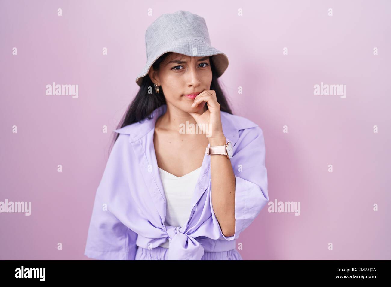 Giovane donna ispanica in piedi su sfondo rosa con cappello che guarda  stressato e nervoso con le mani sulla bocca mordente unghie. problema di  ansia Foto stock - Alamy