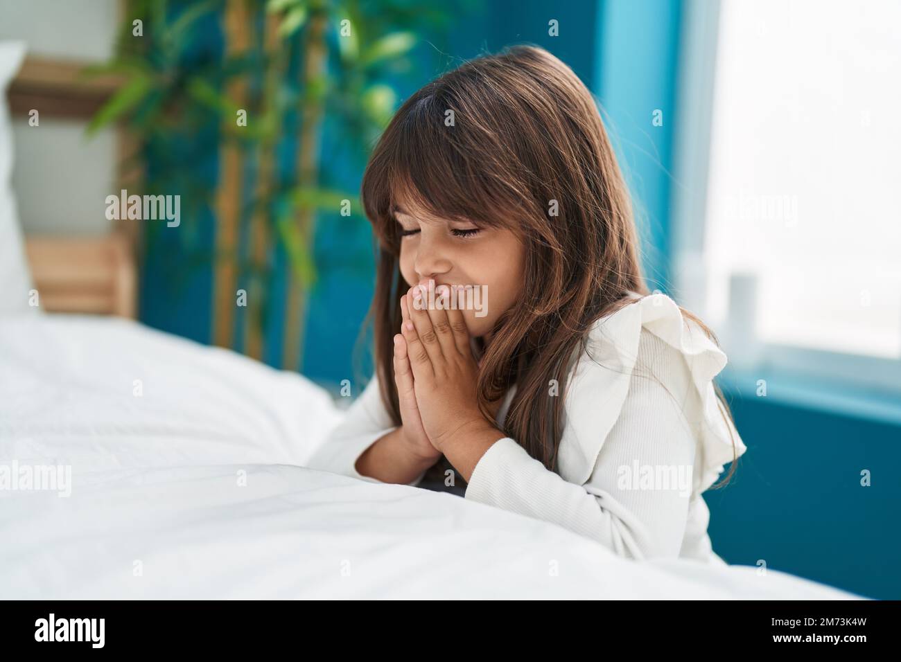 Adorabile ragazza ispanica che prega a letto in camera da letto Foto Stock