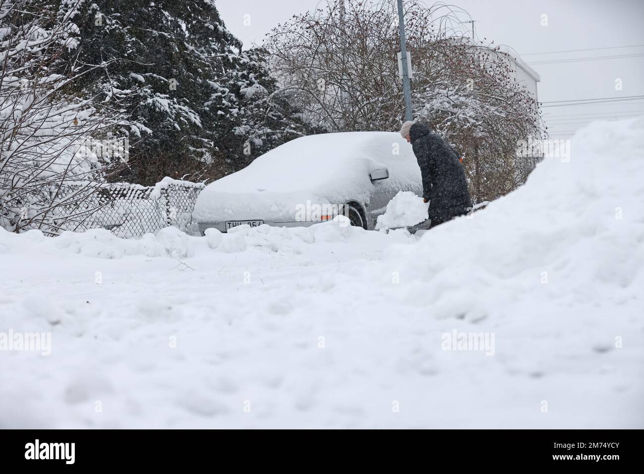 Tempo stagionale, nevicate abbondanti a Motala, Svezia, venerdì pomeriggio. Una donna spala la neve da un'auto coperta di neve. Foto Stock