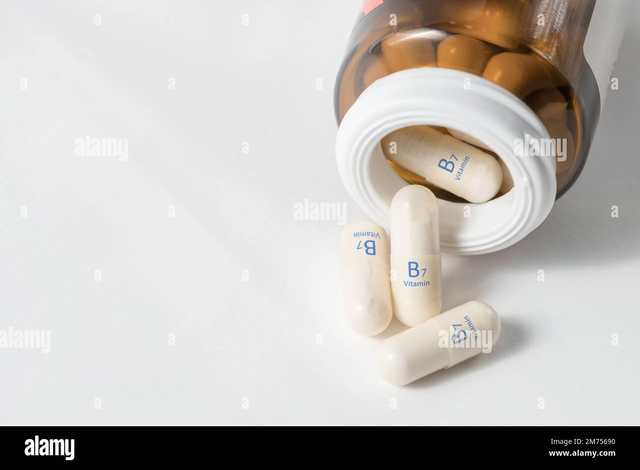 Vitamina B7. Capsule con biotina, necessarie per il metabolismo e la produzione di acidi grassi. Capsule bianche di vitamina B7 o biotina sono disperse sul Foto Stock