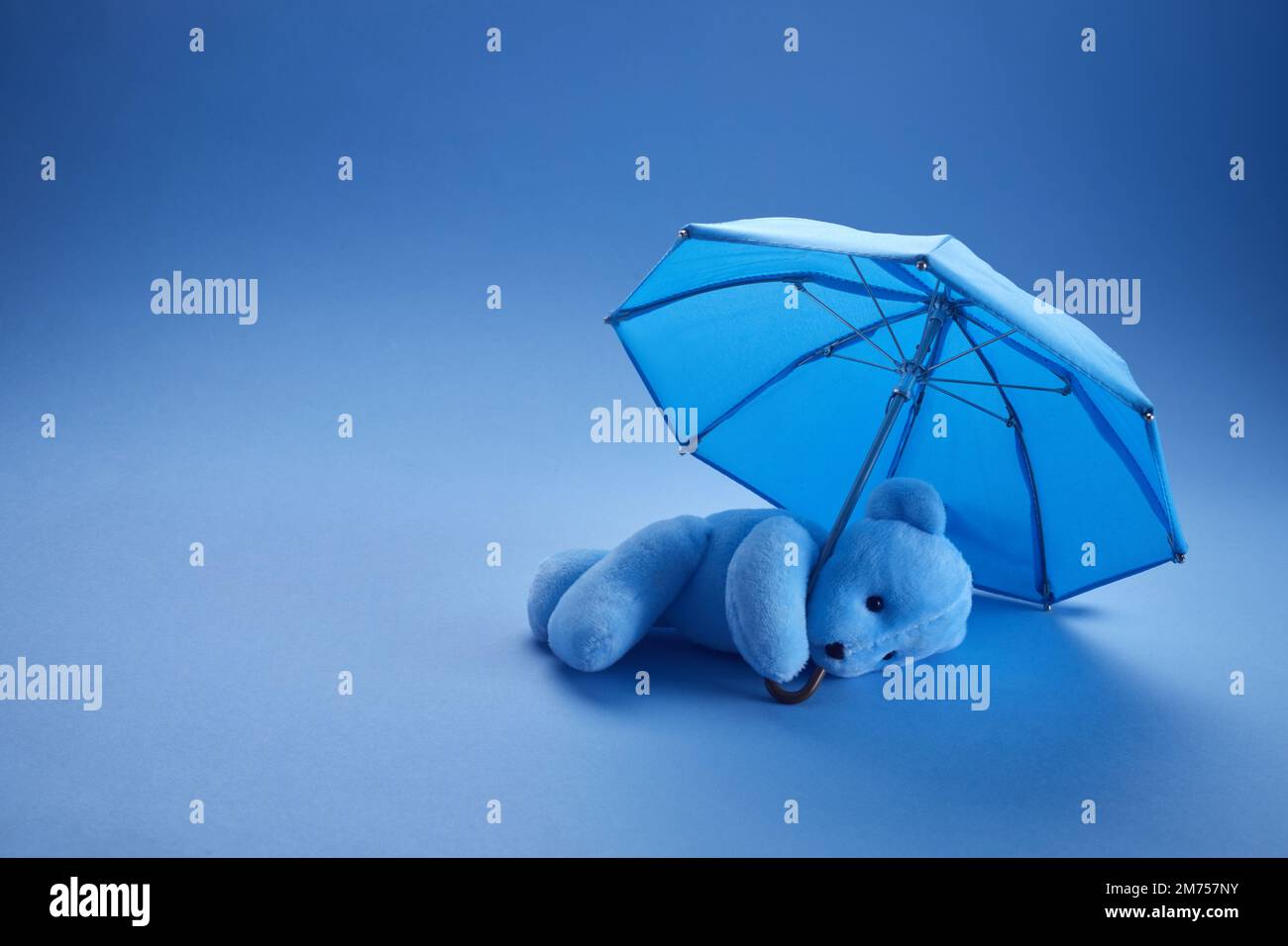 Orsacchiotto blu con ombrello su sfondo blu. Concetto di lunedì blu. Foto Stock