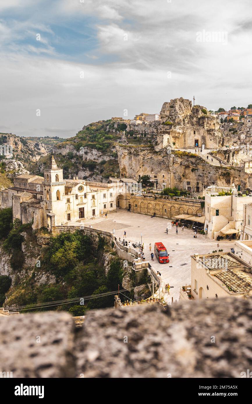 Uno scatto verticale della bellissima città di Matera in Italia con abitazioni scavate nelle grotte e un paesaggio nuvolato Foto Stock