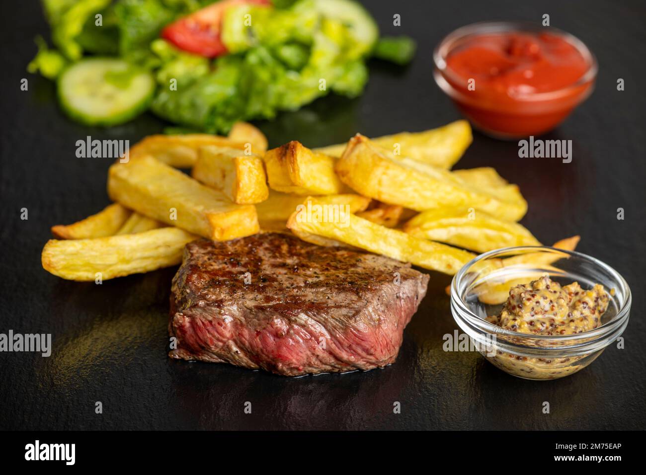 bistecca con patatine fritte sull'ardesia Foto Stock