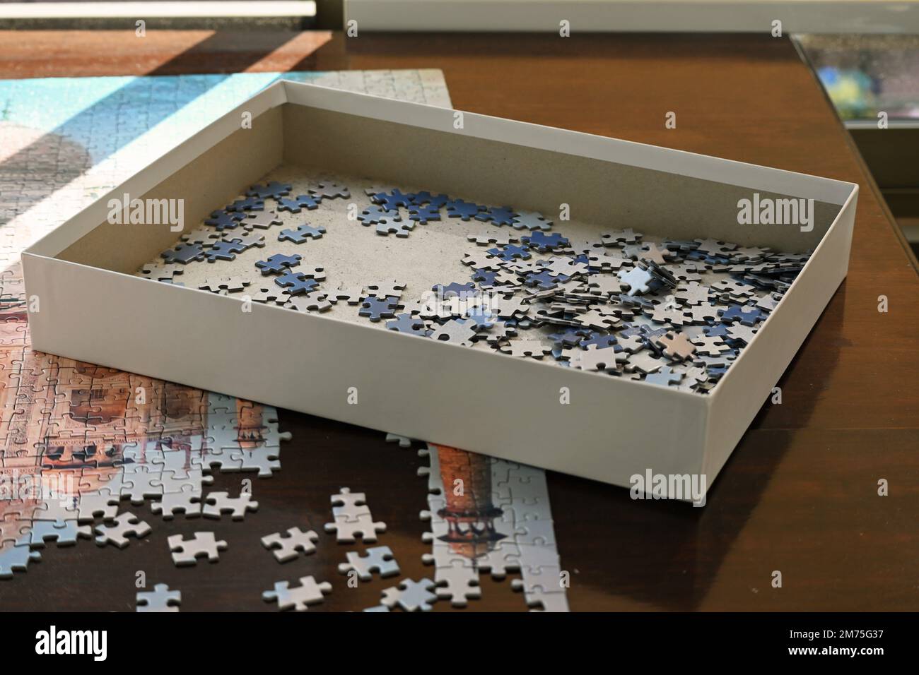 Scatola di pezzi di puzzle su un tavolo Foto Stock