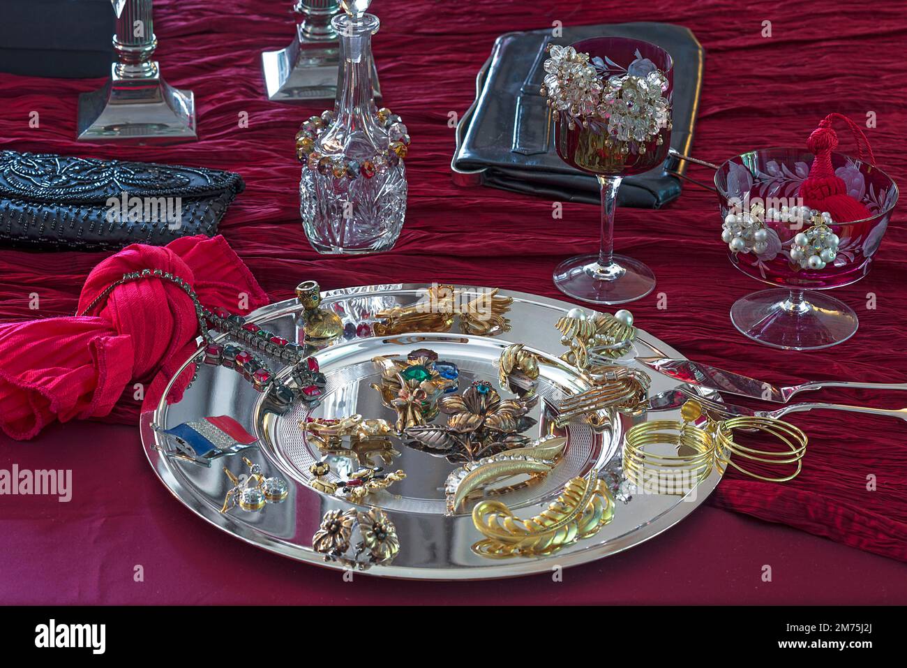 Gioielli in pietra di rhinestone e accessori decorati su un piatto d'argento e un panno rosso, Baviera, Germania Foto Stock