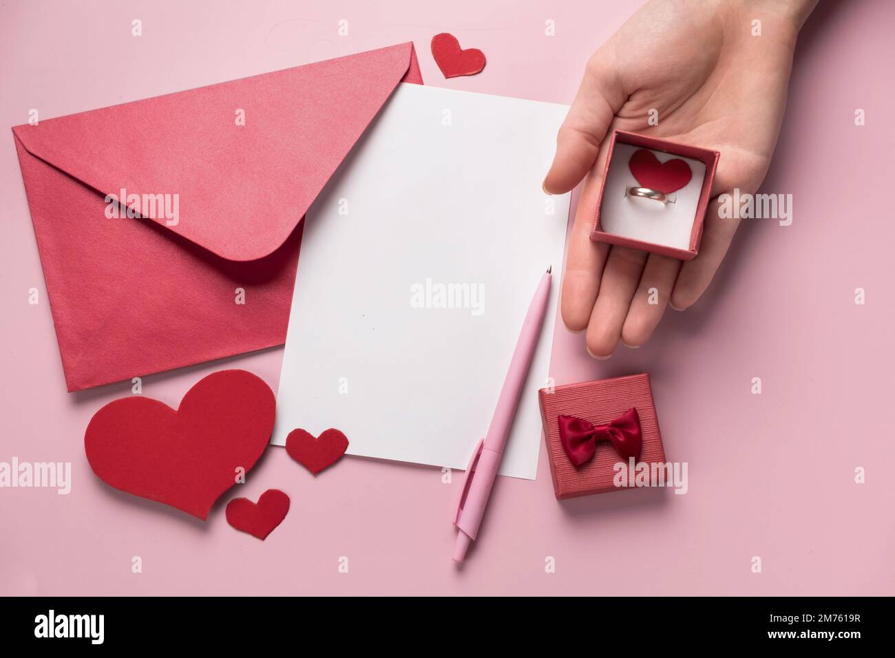 Regalo di San Valentino in scatola, lettera e busta con spazio per la copia su sfondo rosa. Anello per la proposta di matrimonio, piatto. Invito di nozze Foto Stock