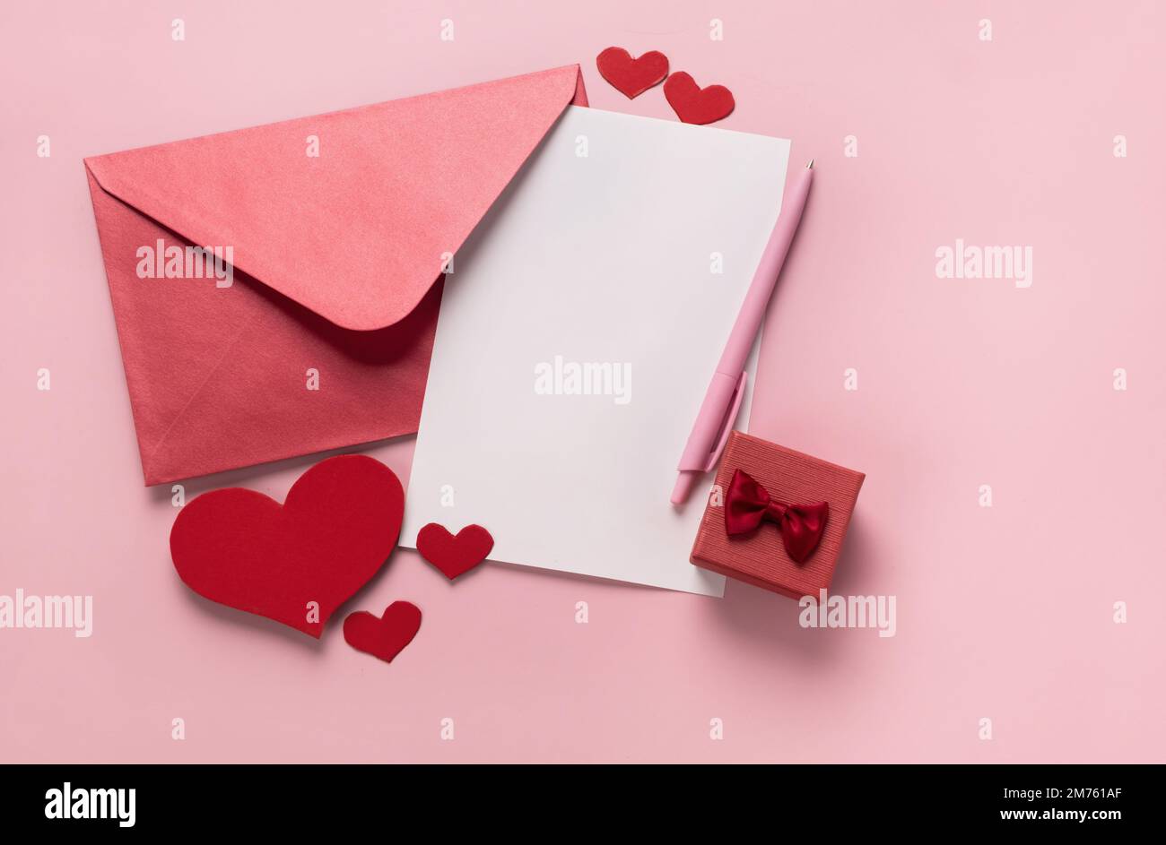Regalo di San Valentino in scatola, lettera e busta con spazio copia su sfondo rosa. Anello per la proposta di matrimonio, piatto. Invito di nozze Foto Stock