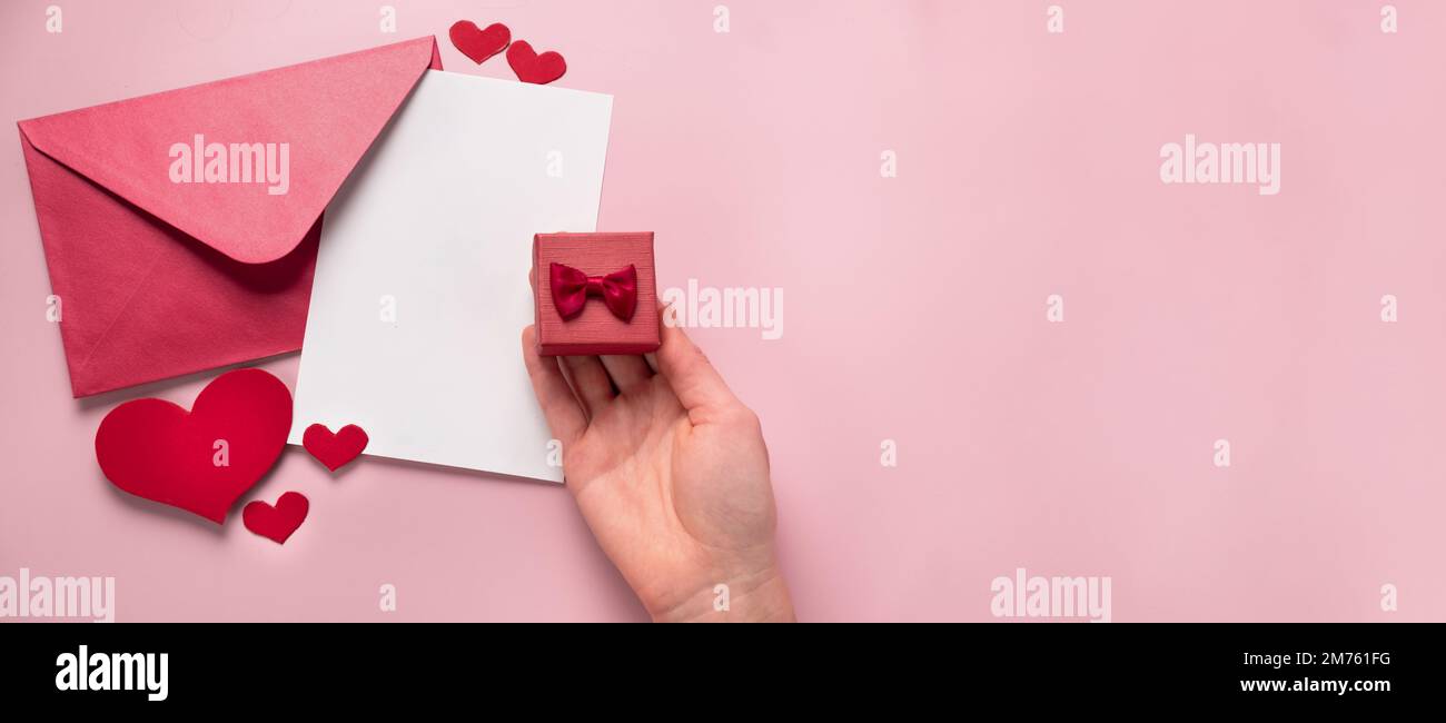 Regalo di San Valentino in scatola, lettera e busta con spazio per la copia su sfondo rosa. Proposta di matrimonio, piatto. Invito di nozze Foto Stock