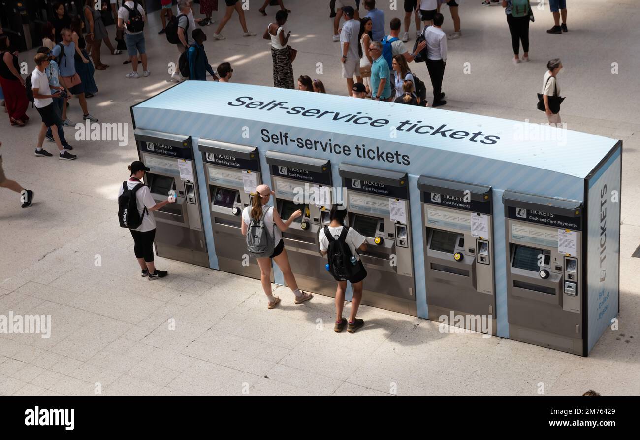 Persone che acquistano i biglietti da distributori automatici di biglietti all'interno della stazione di Waterloo Foto Stock