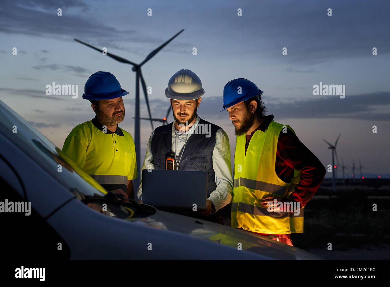 Il gruppo di ingegneri nel ha discusso il piano per la manutenzione di turbine eoliche che funzionano con un computer portatile Foto Stock