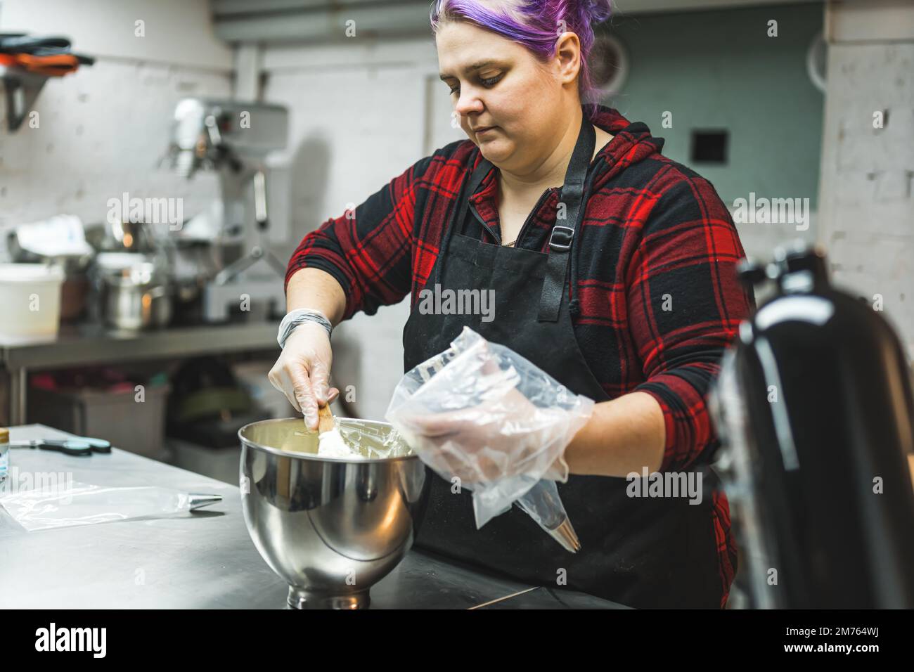 Persona che riempie sacchetto di pasticceria usa e getta con crema di burro glassa per decorare cupcake e crostate. Chef professionista in cucina. Foto di alta qualità Foto Stock
