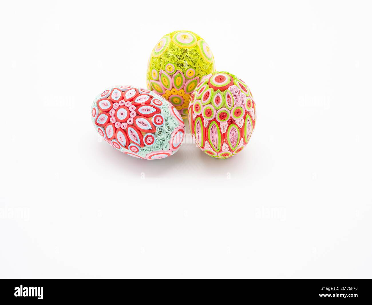 Tre uova di Pasqua color pastello con due piedi e una sul suo lato su uno sfondo bianco. L'immagine ha spazio di copia. Foto Stock