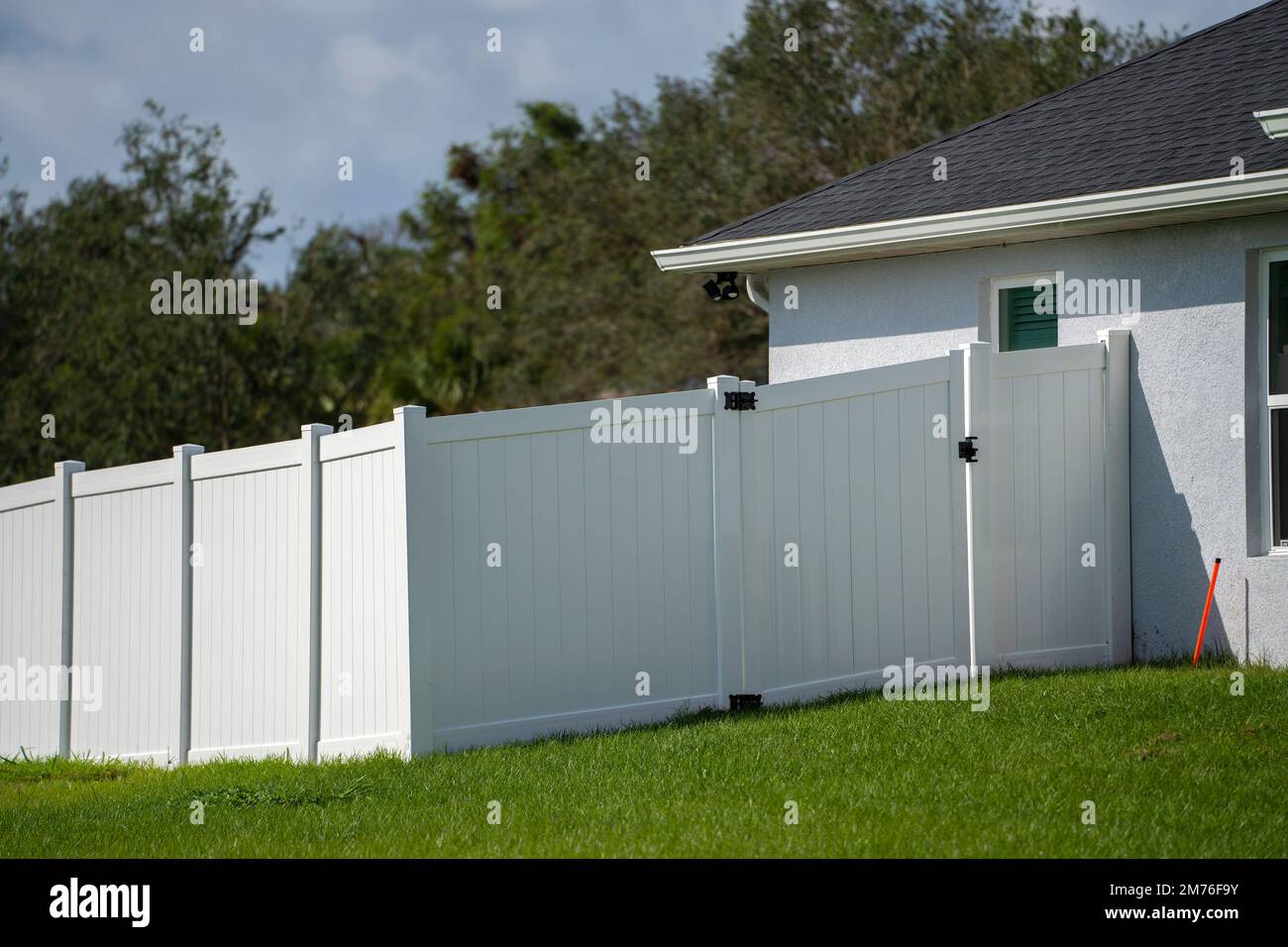 Recinzione in vinile bianco sul prato verde che circonda i terreni della proprietà per la protezione del cortile e la privacy Foto Stock