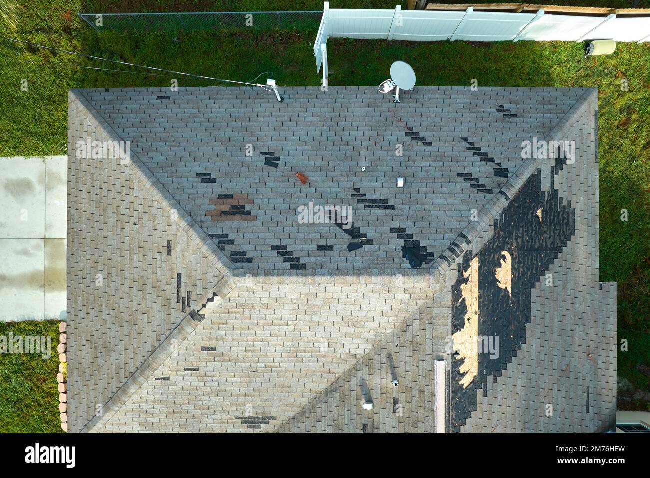 Vento danneggiato tetto casa con scandole di asfalto mancanti dopo l'uragano Ian in Florida. Riparazione del concetto di casa sul tetto Foto Stock