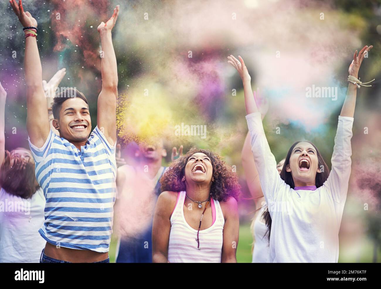 Inseguire l'arcobaleno. amici felici che si divertono con la vernice in polvere. Foto Stock
