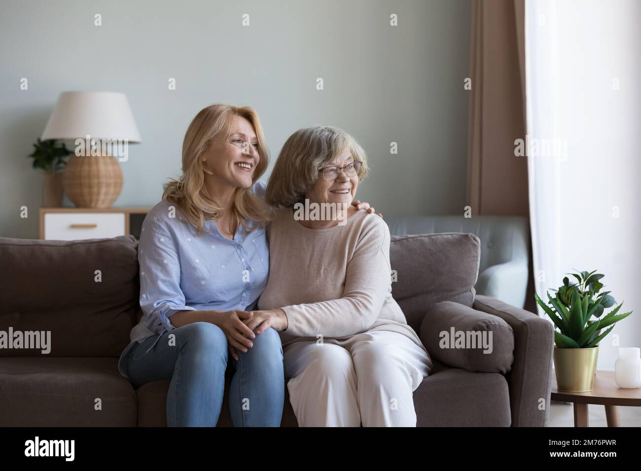 Donna figlia felice e mamma anziana seduti sul divano Foto Stock
