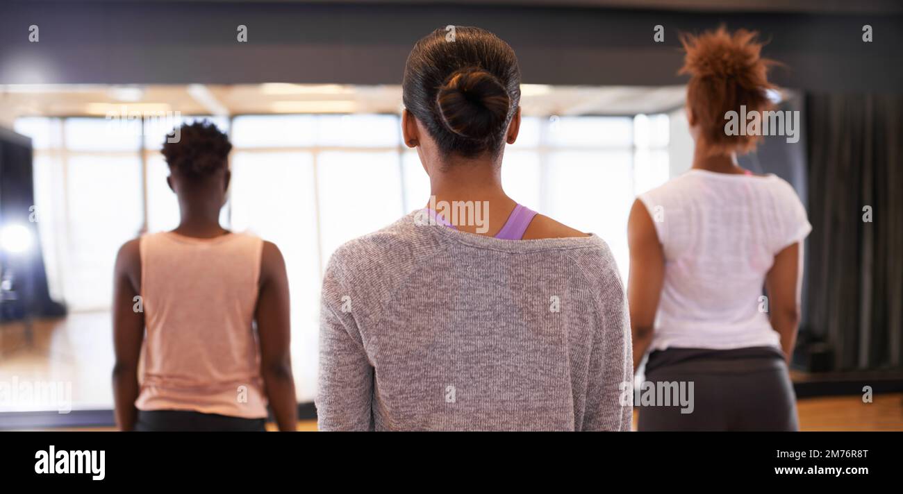 Nel bel mezzo di un fantastico allenamento. Immagine posteriore di un gruppo di giovani ballerini in piedi insieme in uno studio. Foto Stock