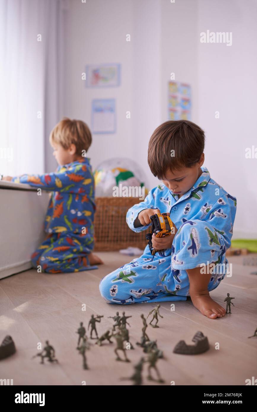 Gioco parallelo. Due fratelli seduti sul pavimento che giocano  separatamente con i loro giocattoli Foto stock - Alamy