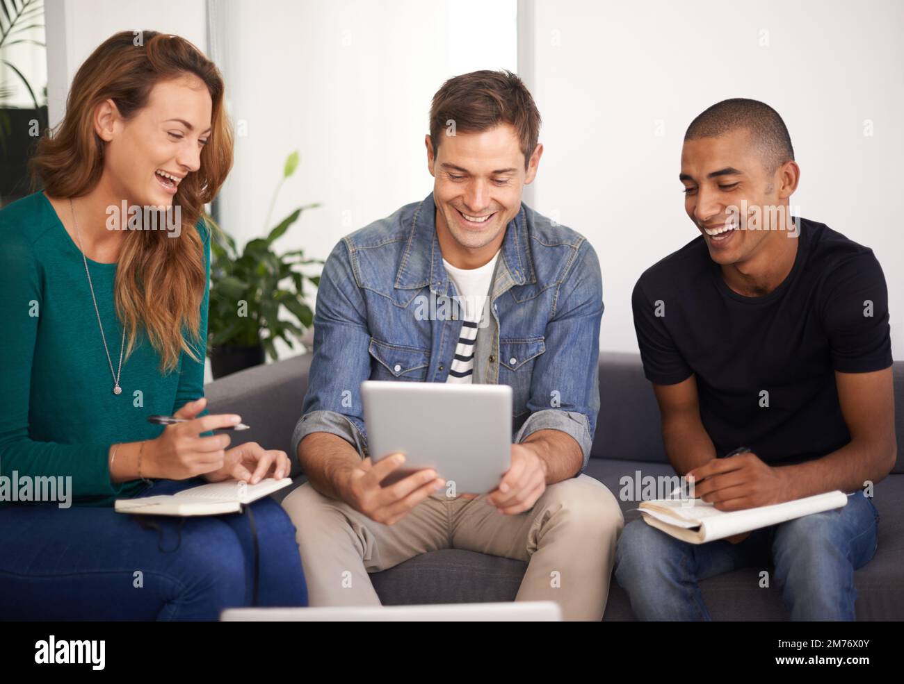 Ottimo lavoro. Un team di giovani professionisti che utilizzano la tecnologia in una riunione informale. Foto Stock