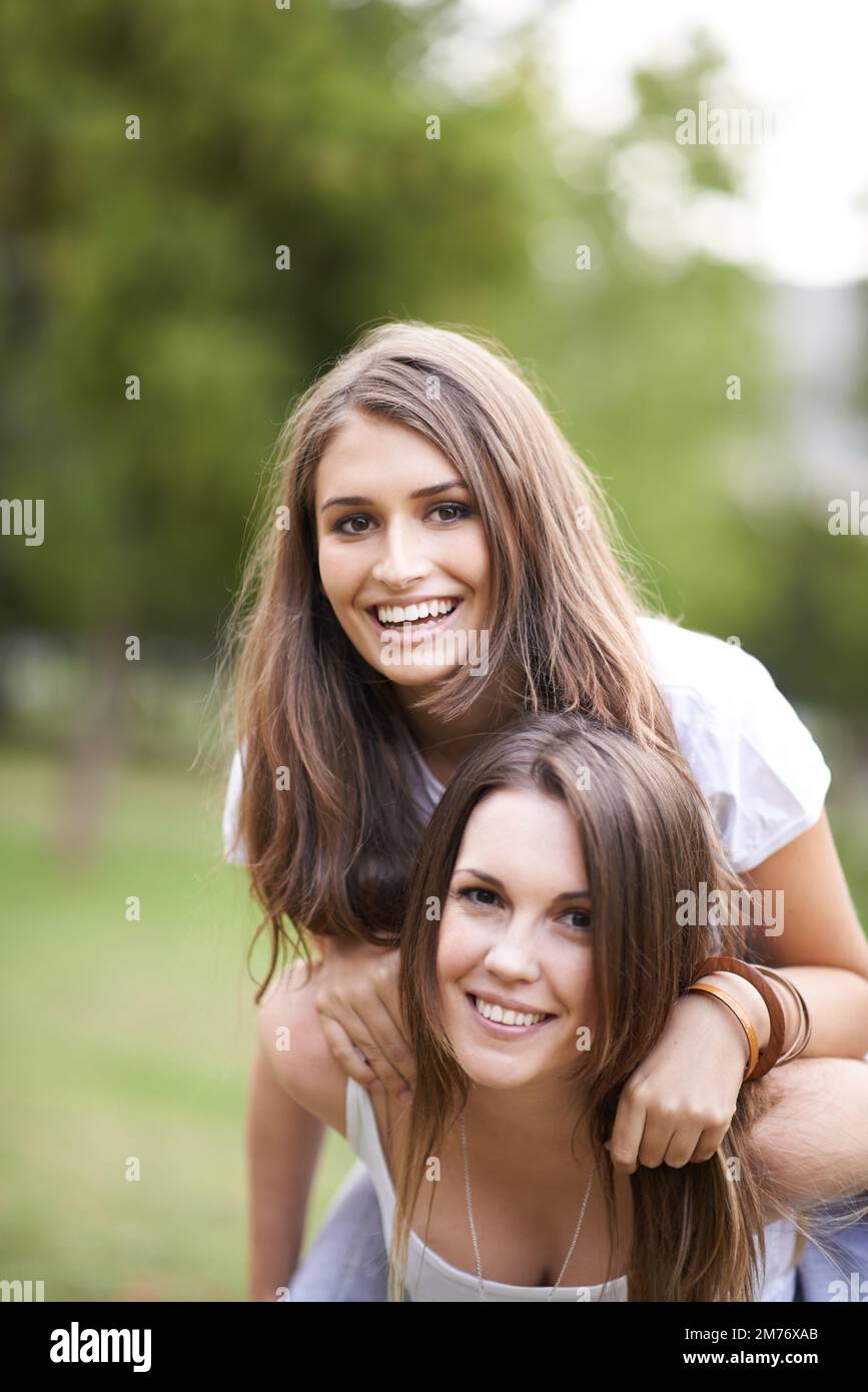 Bella e vivace e piacevole la vita. una giovane donna che dà alla sua amica un giro in piggyback al parco. Foto Stock