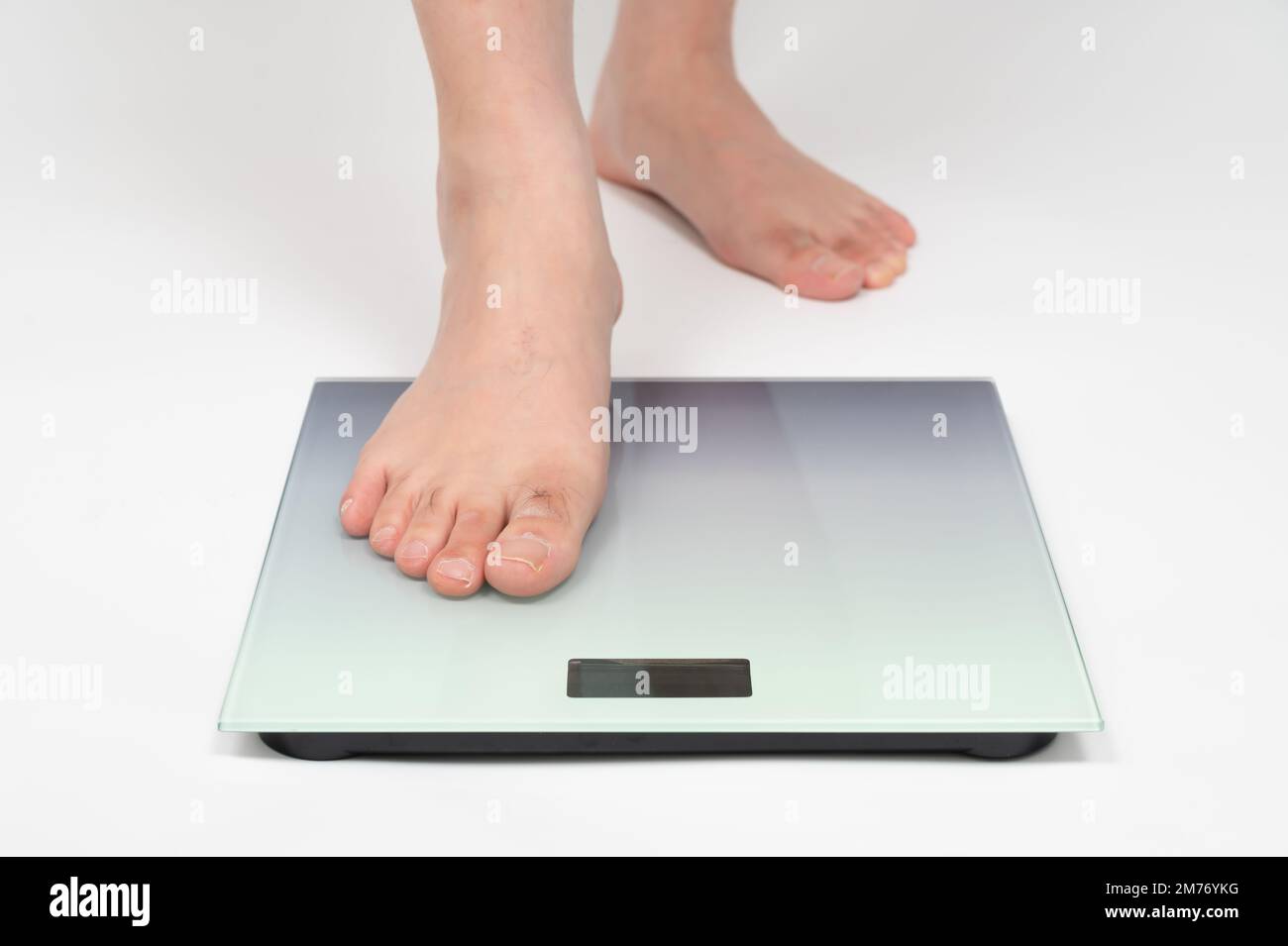 I piedi dell'uomo di mezza età asiatico misurano il peso Foto Stock