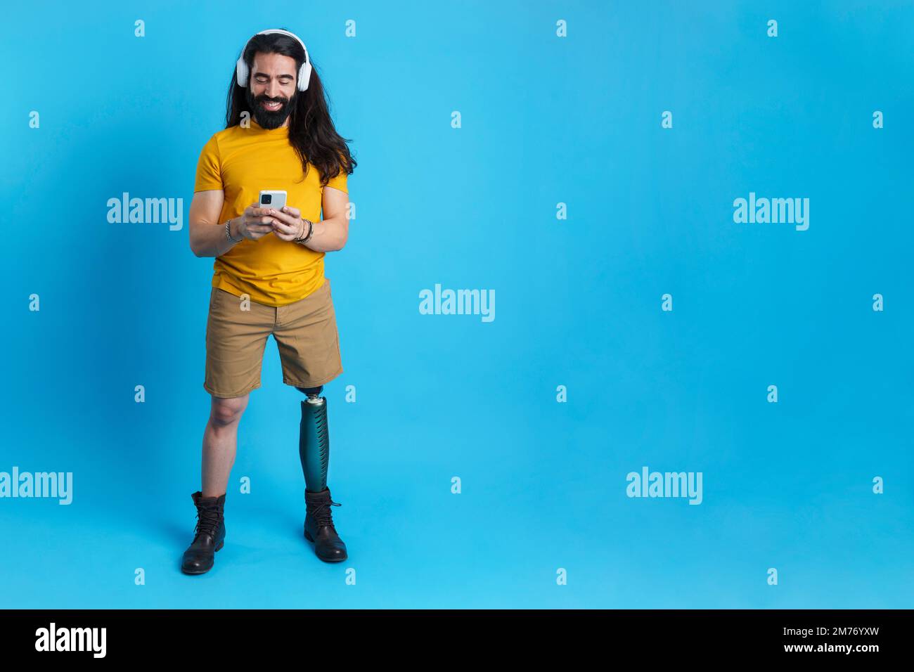 Uomo con protesi delle gambe che ascolta musica con il cellulare Foto Stock