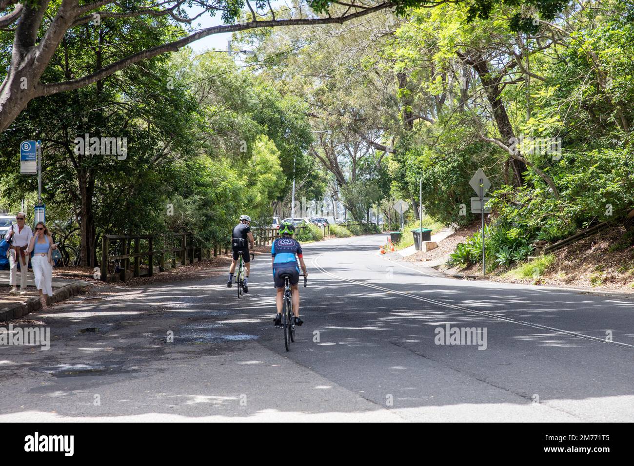 Giovane uomo e giovane donna in bicicletta lungo Pittwater Road a Church Point, Sydney, NSW, Australia Foto Stock