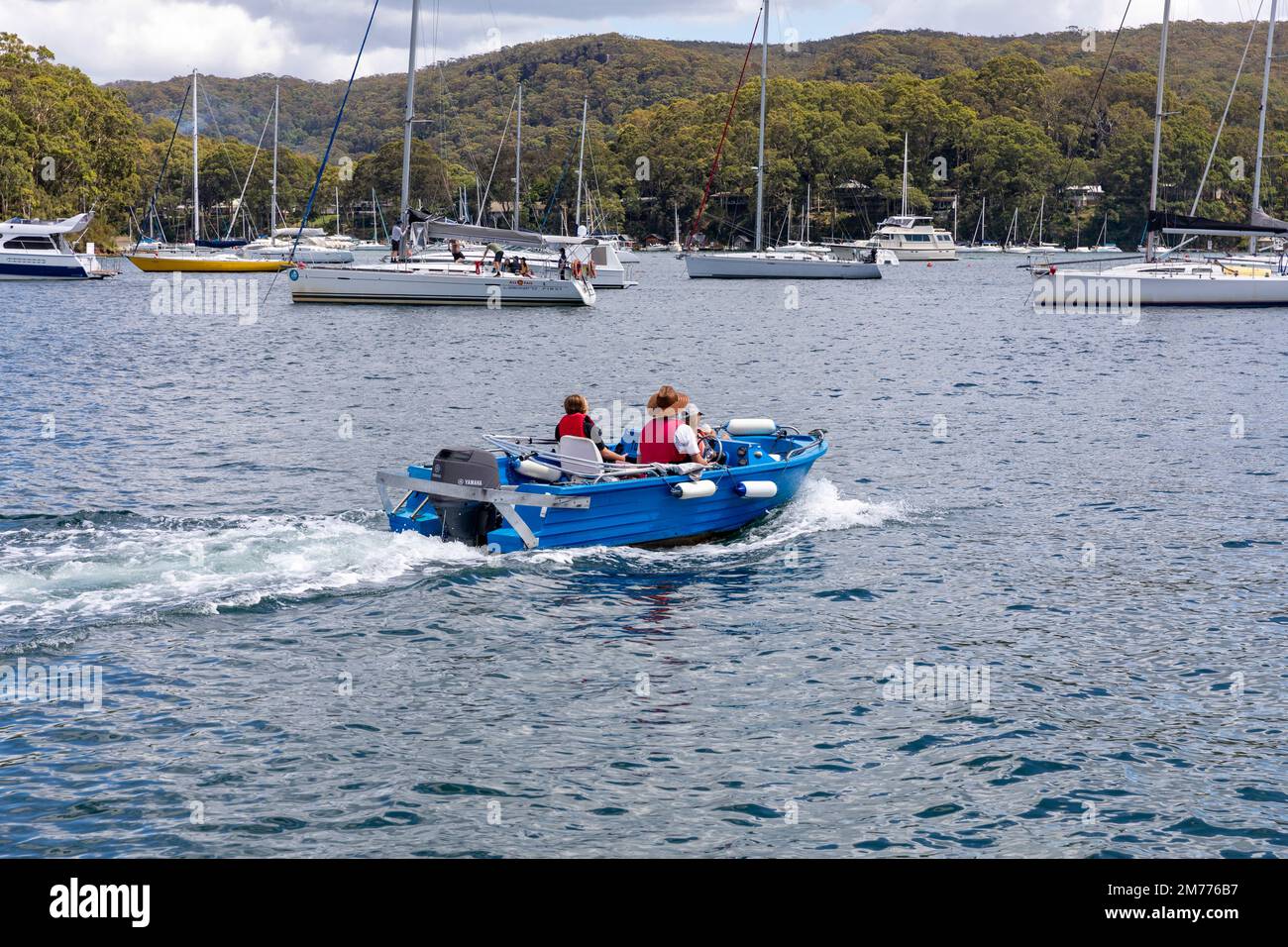 Padre e due bambini in una piccola barca run about policraft su Pittwater, visto da Church Point, yacht ormeggiati in background, Sydney, NSW, Australia Foto Stock