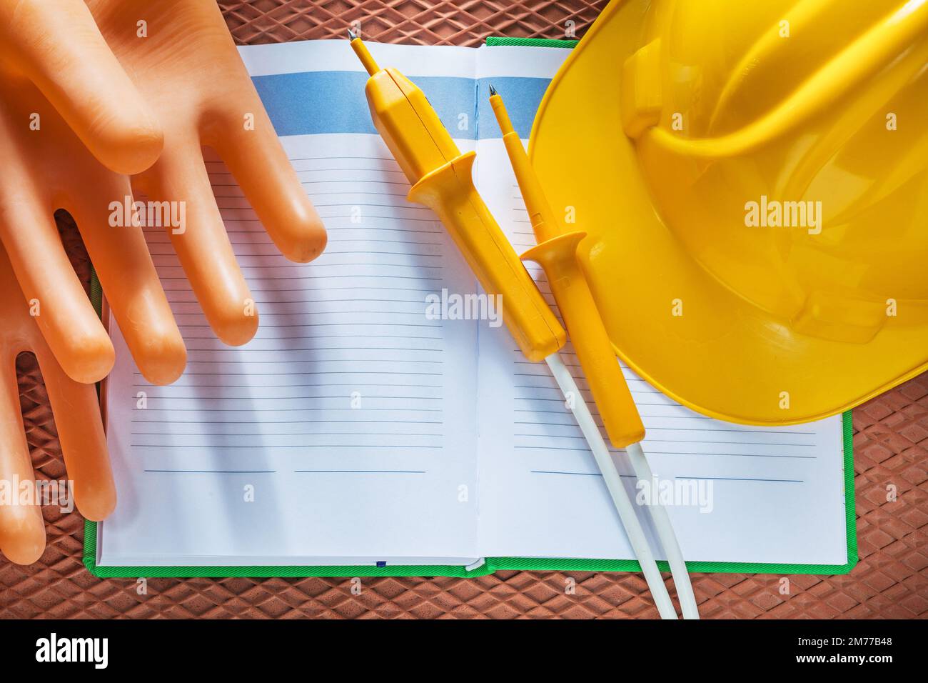 Guanti isolanti in elmetto per notepad tester elettrico su tappetino dielettrico. Foto Stock