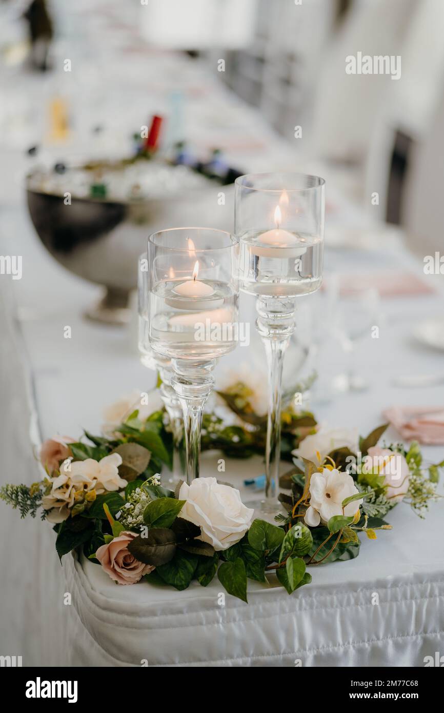 Una foto verticale di portacandele e fiori di vetro su un tavolo per matrimoni Foto Stock