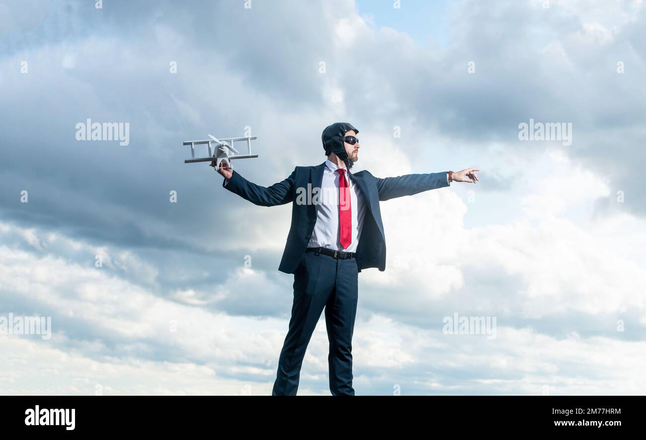 uomo d'affari in tuta e cappello pilota lancio aereo giocattolo su sfondo cielo. libertà Foto Stock