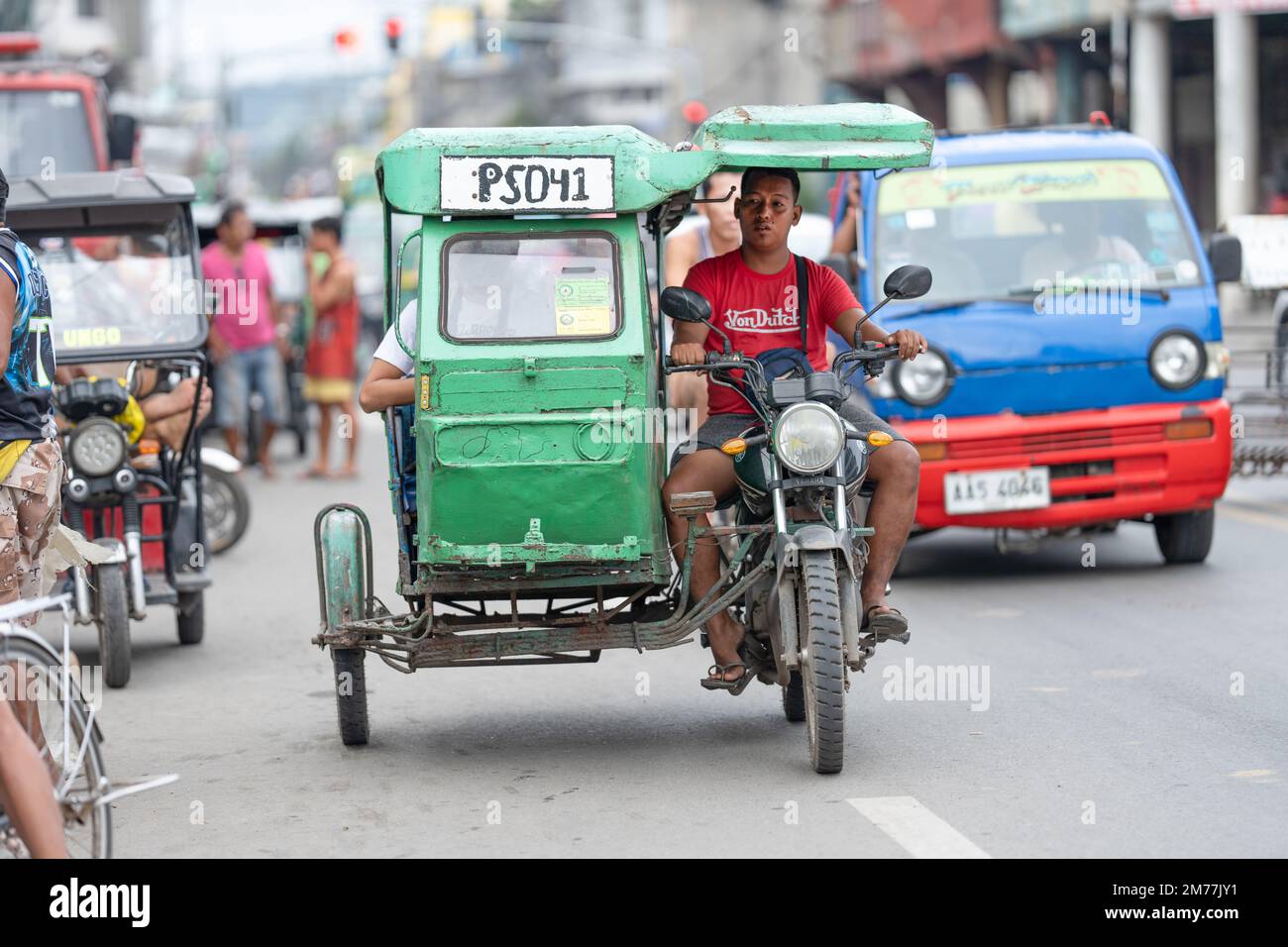 Un uomo che guida un triciclo motorizzato utilizzato come trasporto passeggeri, Cebu City, Filippine Foto Stock