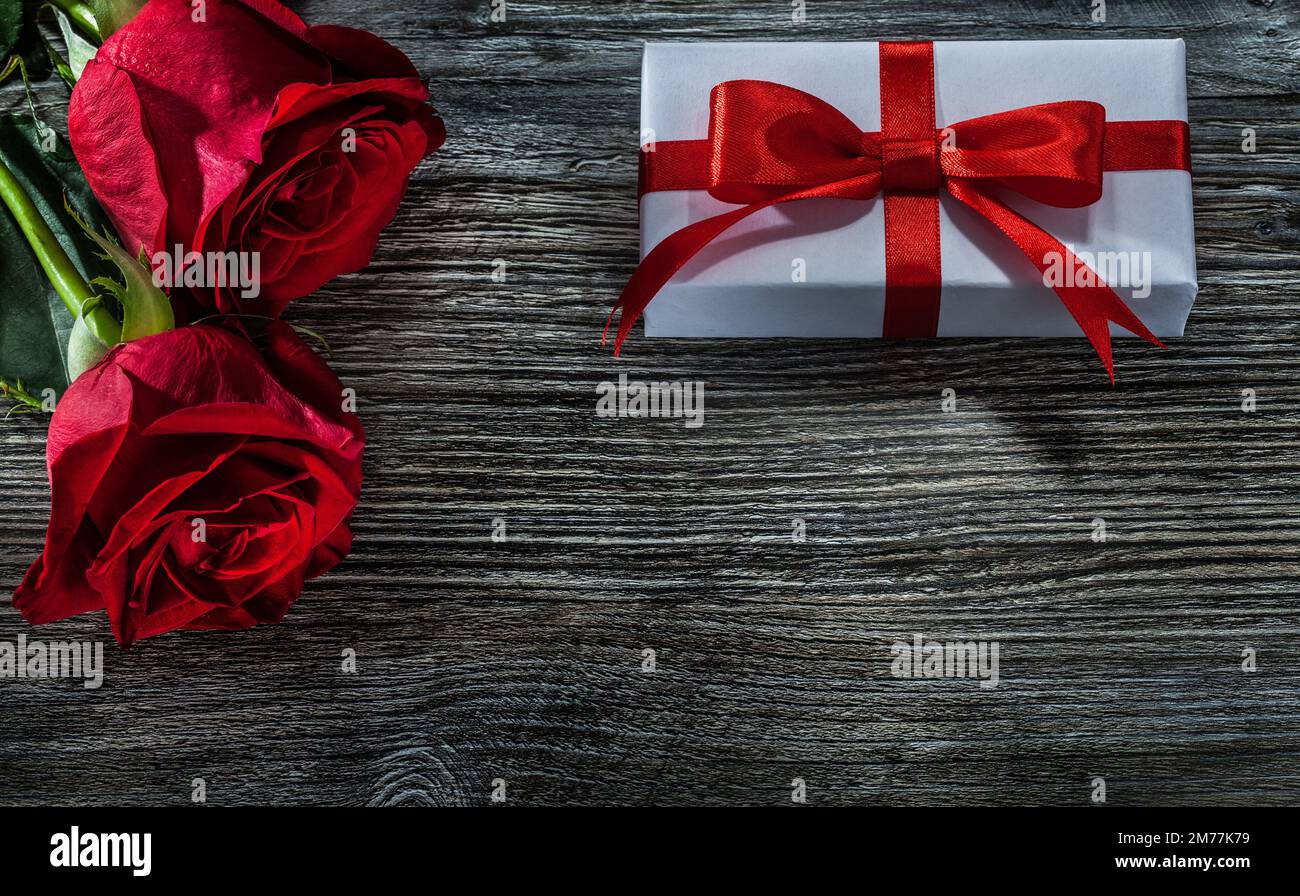 Scatole regalo bianche rose rosse su asse di legno. Foto Stock