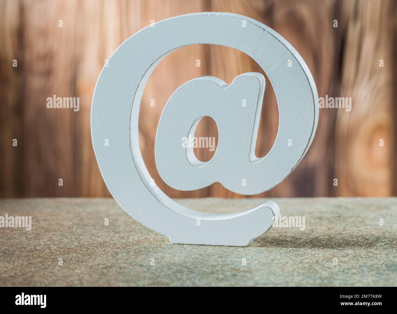 simbolo e-mail in ceramica bianca su sfondo in legno d'epoca Foto Stock