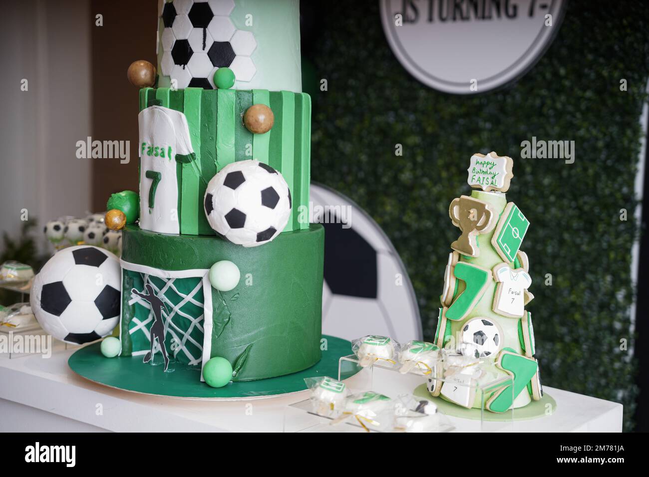 Torta di compleanno di calcio o calcio su un tema decorato con un obiettivo, erba verde, palline da calcio e una T-shirt verde su uno sfondo banner di compleanno. Foto Stock