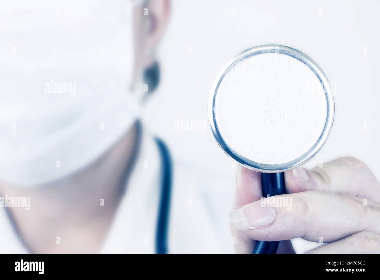 Uno stetoscopio per esaminare un paziente sullo sfondo di un medico in una maschera medica bianca. Concetto di assistenza sanitaria Foto Stock