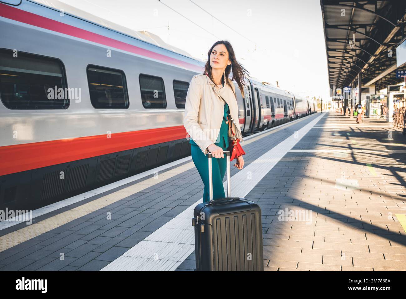 Ritratto di una donna in viaggio d'affari che cammina in una stazione ferroviaria o aeroporto andando al cancello d'imbarco con bagaglio a mano Foto Stock